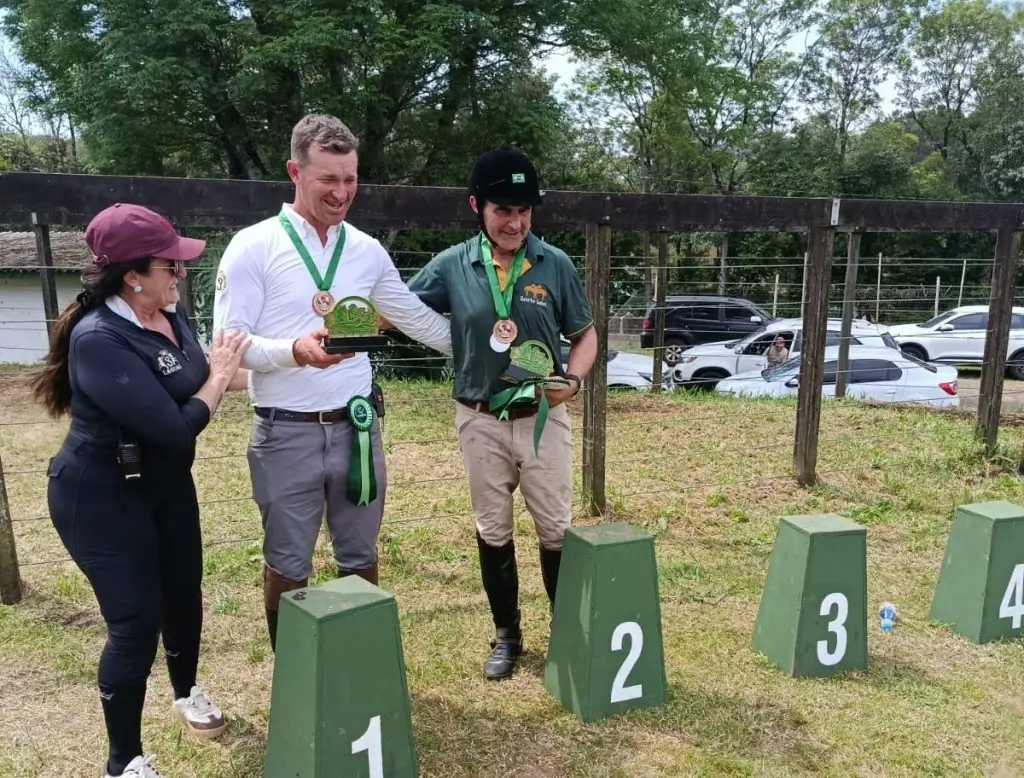 Premiação da prova de salto do hipismo na Expomerco 2026, com competidores medalhados junto ao pódio