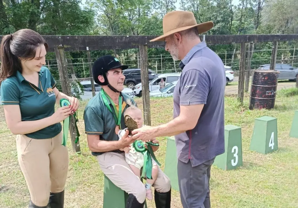 Competidor de capacete e camisa verde recebe premiação durante a prova de salto da Expomerco 2026