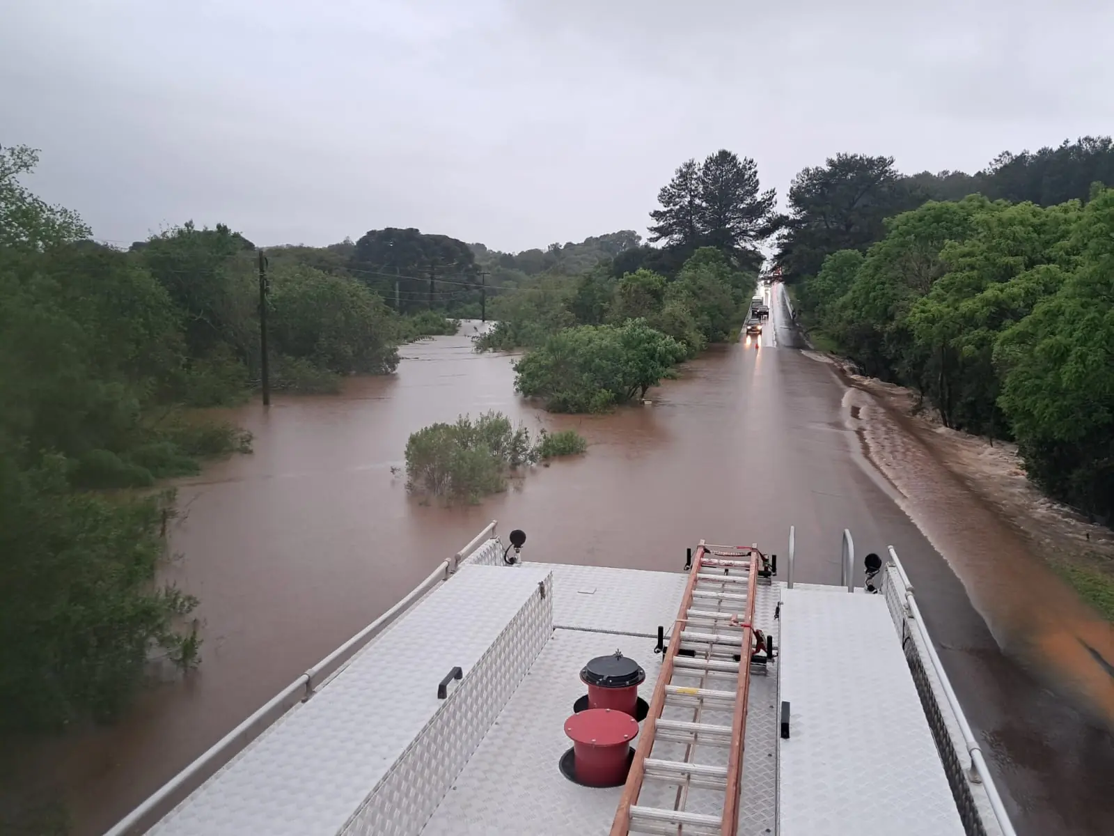 Trecho de rodovia tomado pela água da chuva, visto do alto de um caminhão dos bombeiros
