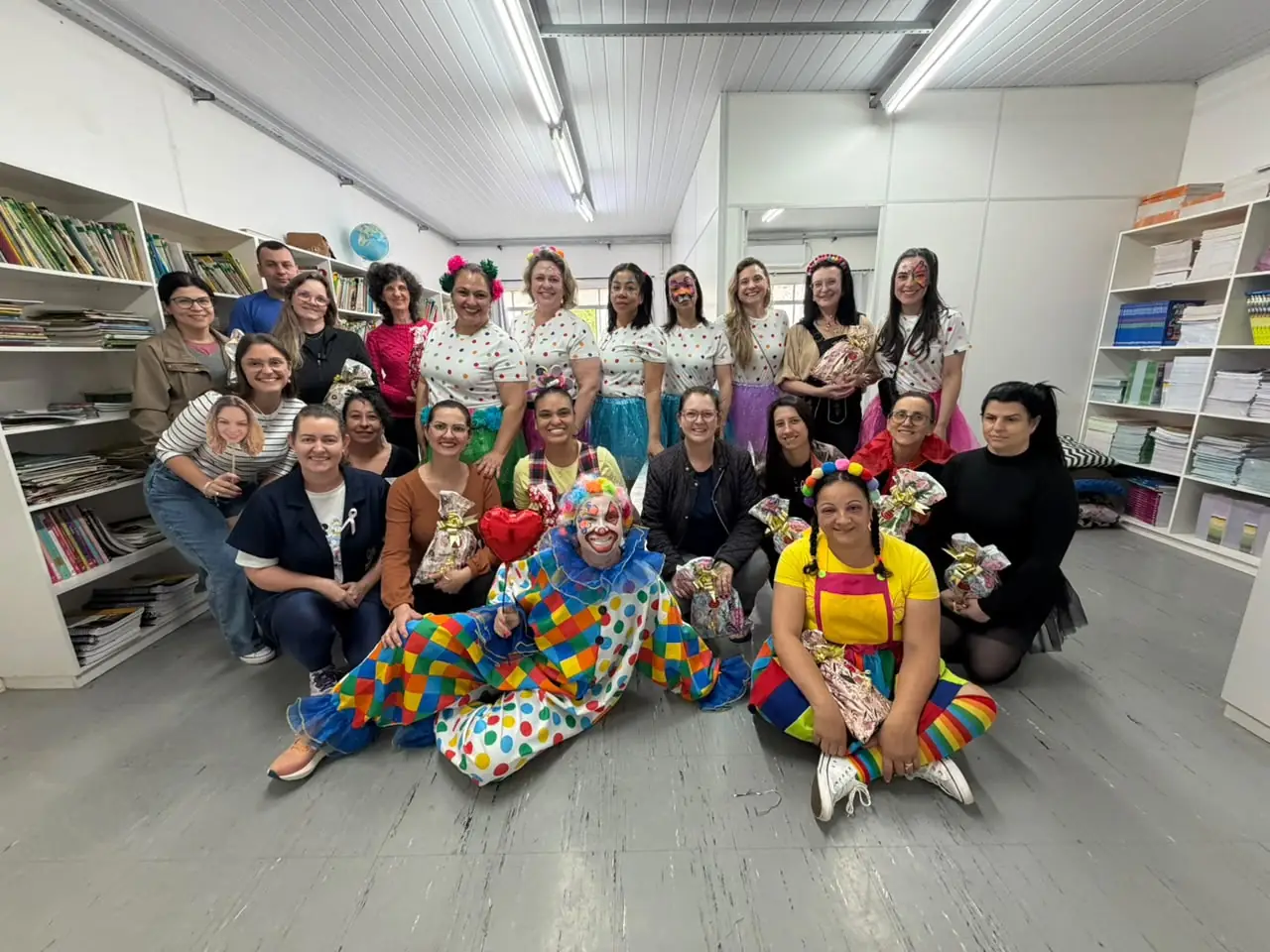 Integrantes da CDL Mulher e professores da Escola Nossa Senhora de Lourdes, com o palhaço, na biblioteca da escola