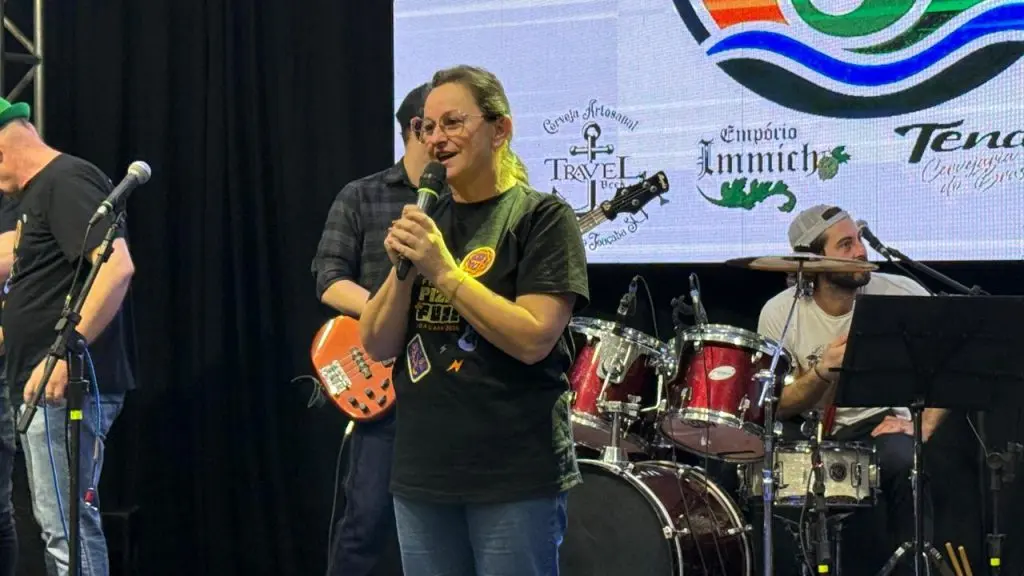 Mulher discursa ao microfone no palco do Pizza & Fuzz