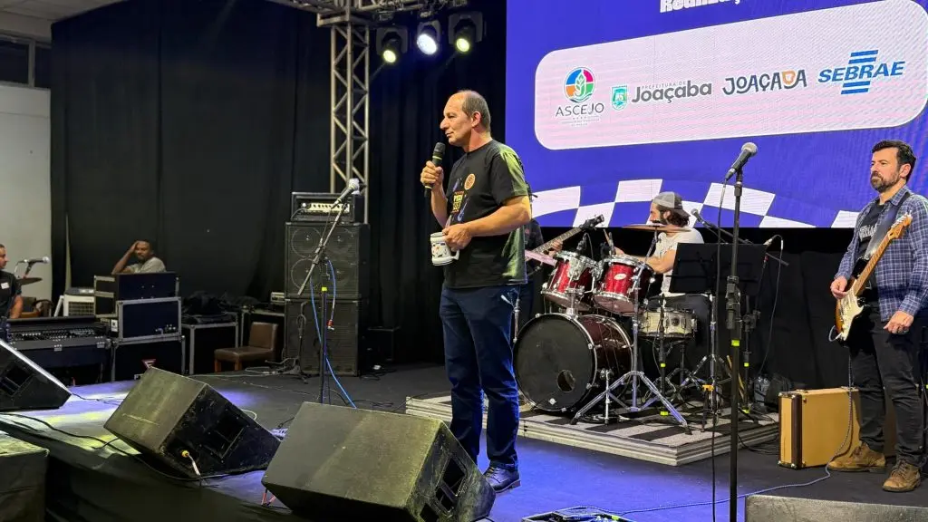 Homem discursa ao microfone no palco do Pizza & Fuzz