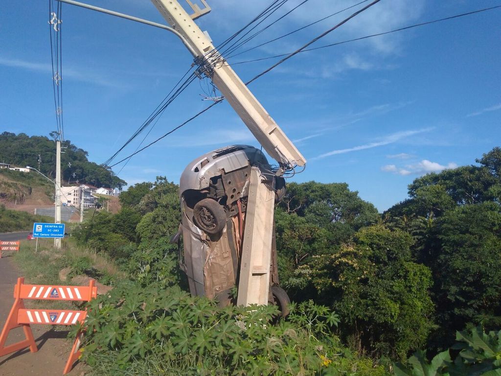 Veículo bate contra poste e fica pendurado na estrutura